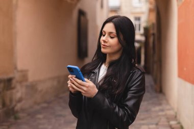Genç, şık bir bayan öğrenci akıllı telefondan mesaj yazıyor. Eski şehir caddesinde yürüyor, hipster turistleri şehirde geziyor ve cep telefonu kullanarak seyahat planlıyor, kız sohbeti yapıyor, haberleri okuyor, mutlu görünüyor..