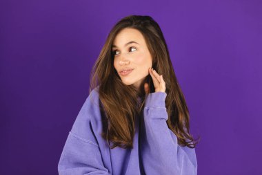 Esmer saçlı güzel kadın sağlıklı, doğal, güzel cilt bakımı yaptırıyor. Dişi güzel, doğal makyajlı, genç bir model. Mor arka planda izole edilmiş güzelliği yakından görüyor. Kız yana bak..