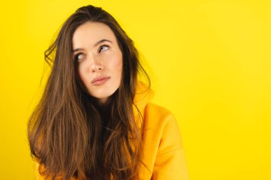 Sarı kapüşonlu yuvarlak gözlü, sinirli, genç, siyah saçlı, kederli bakışlı bir kadın. İnsanların yüz ifadeleri, duyguları ve duyguları. Yorgunluk ya da bıkkınlık kavramı.