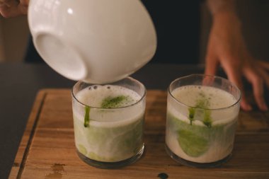 Ahşap güvertede iki bardak yeşil kibrit sütlü sütlü çay. Maç sütle hazırlanıyor.