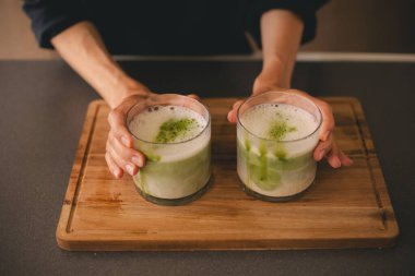 Tahta güvertede iki bardak yeşil kibrit sütlü latte çayı..