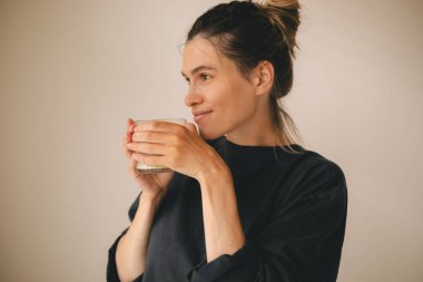 Rahatlamış genç bir kadın sabahları evde sütlü sütlü sütlü çayını kokluyor. Topuzlu kız siyah bluz giyiyor..