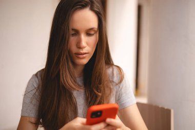 Cep telefonu tutan ve evin yanında otururken akıllı telefona bakan genç ve güzel bir kadın. Ciddi bir kız cep telefonu kullanıyor ve flört ediyor gibi görünüyor. Kadın sakin ol, telefonu tut, haberleri oku, mesajı ver..