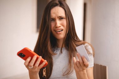 Kumral, uzun saçlı, kısa saçlı bir kadın kredi kartı kullanıyor. Akıllı telefon, e-ödemeyle ilgili sorunlar yaşıyor. Parasızlık, ödeme güvensizliği, yetersiz fonlar yüzünden kendini rahatsız hissediyor. Dolandırıcılık mağduru..