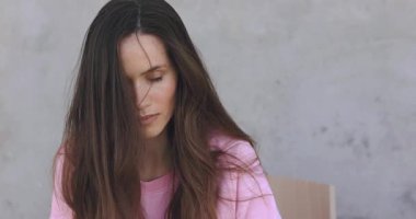 Sevimli, kumral, uzun saçlı kadın, şakacı bir şekilde göz kırpıyor, flört ediyor. Kıvırcık saçlı modelin yüzü gülümsüyor ve pembe bluz giyiyor. Kız gözlerini aç, kameraya ciddi bak, gülümsemeye başla..