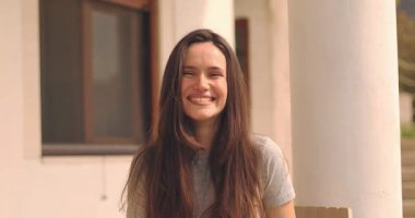 Genç, heyecanlı, neşeli esmer kadın, kameraya bak, gül, gülümse, şaka yap, işaret parmağınla evinin yanında otur.. 