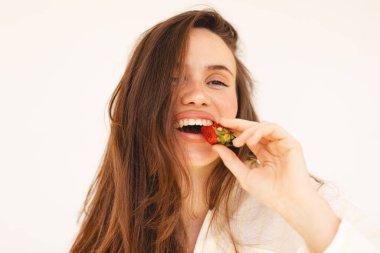 Esmer, uzun saçlı bir kadın çilek, beslenme ve sağlıklı yaşam için C vitamini, organik meyve ve sağlıklı beslenmek için beslenme ve beslenme için gülümseme yer. Mutlu gülen kız.