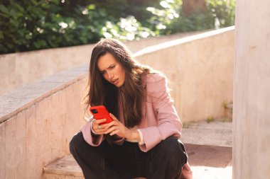 Merdivenlerde cep telefonu kullanan çılgın ve şok edici genç esmer bir kadın. Mutsuz kadının cep telefonu var. Hayal kırıklığına uğramış üzgün bayan, haberleri dehşete düşürdü. Bu da ne? Olamaz..