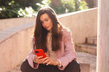 Merdivenlerde cep telefonu kullanan çılgın ve şok edici genç esmer bir kadın. Mutsuz kadının cep telefonu var. Hayal kırıklığına uğramış üzgün bayan, haberleri dehşete düşürdü. Bu da ne? Olamaz..