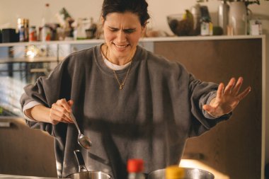 Mutfakta afete uğrayan genç bir ev hanımı şoka girdi ve akşam yemeği hazırladı. Acelesi olan kadın, üzgün ve kızgın görün..