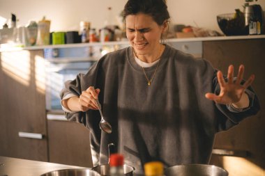 Mutfakta afete uğrayan genç bir ev hanımı şoka girdi ve akşam yemeği hazırladı. Acelesi olan kadın, üzgün ve kızgın görün..