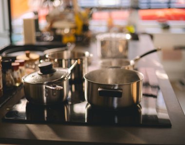 Ev mutfağındaki elektrikli ocağın üzerinde paslanmaz çelik tencereler. Akşam yemeğinde, öğle yemeğinde ya da kahvaltıda yemek yapmak.. 