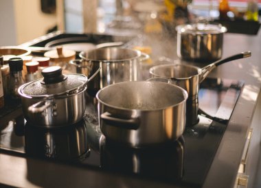 Ev mutfağındaki elektrikli ocağın üzerinde paslanmaz çelik tencereler. Akşam yemeğinde, öğle yemeğinde ya da kahvaltıda yemek yapmak.. 