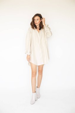 Çekici esmer kadın bej gömlek giyiyor. Sokak modası. Seksi kıyafetler giyen bir manken. Her günkü zarif görünüşün ayrıntıları. Kıvırcık kısa saçlı, yürüyen ve poz veren seksi esmer kadın..