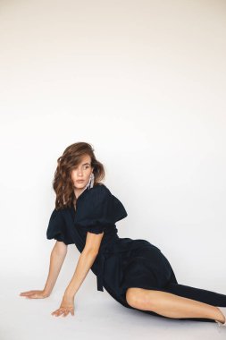 Her günkü zarif görünüşün ayrıntıları. Gündelik kıyafet giyen bir manken. Moda minimalist tarzda kabarık kollu lacivert bir elbise. Fener kollu bir kadın oturuyor.