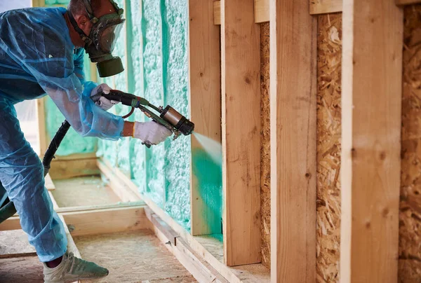 男性建筑工人为木制框架房屋隔热 男工在未来的小木屋内喷涂聚氨酯泡沫 使用多元组件枪 建筑和绝缘概念 — 图库照片