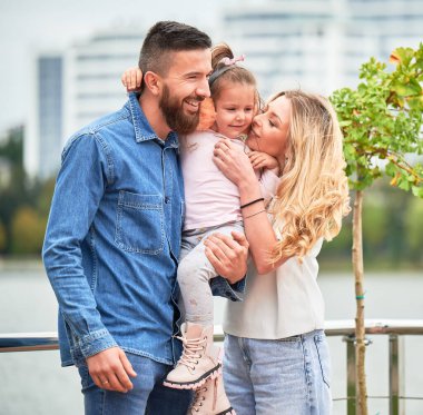 Dışarıda çocuklu mutlu bir aile babası ve kadın. Baba, göl kenarındaki yeni kentsel bölgede ailesiyle vakit geçirirken çok tatlı bir çocuğu kucağına alıyor..