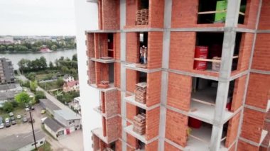 Karısı ve çocuğu olan bir adam inşaat halindeki bir binanın içinde duruyor. Yeni inşa edilmiş apartmanı ve yeni aile sakinleri olan emlak alıcıları olan şehir merkezi. Drone görünümü