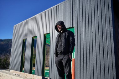 Erkek mühendis ahşap çerçeve inşa ediyor. İnşaat alanında duran adam, çalışma kalitesini denetliyor..