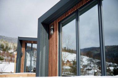 İskandinav modern tarzında geniş pencereli iki ahşap ev. Dışarıdan. Ahır evi.