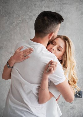 Evin anahtarlarını tutan kadın ve yeni dairesinde kocasını kucaklayan kadın. Mutlu çift kucaklaşıyor ve emlak alımını kutluyor. Aşk kavramı, yeni ev ve mülk alımı.