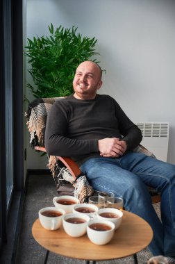 Çağdaş ahır evinde hafta sonları eğlenen genç bir adam. Yeni kulübede sandalyede oturan mutlu bir erkek turist..