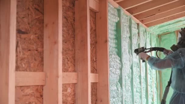Male Builder Insulating Wooden Frame House Man Worker Spraying Polyurethane — Stockvideo
