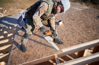 Marangoz tahta işletim tahtası kesmek için testere kullanıyor. Ahşap çerçeve inşa eden bir işçi. Marangozluk kavramı.