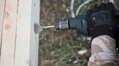 Ahşap çerçeve inşa eden adam. Gelecekteki kulübelerin ahşap çerçevesinde elektrikli matkapla delik açan işçiler. Marangozluk kavramı.