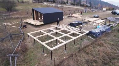 Erkek işçiler temel üzerine ahşap çerçeve inşa ediyorlar. Marangozlar çekiç kullanarak ahşap kiriş takıyorlar. Marangozluk kavramı.