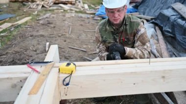 Ahşap çerçeve inşa eden adam. Gelecekteki kulübelerin ahşap çerçevesinde elektrikli matkapla delik açan işçiler. Marangozluk kavramı.