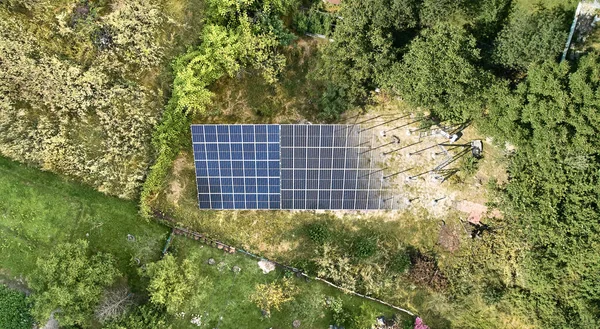 Aerial view of solar module fading away and shifting into metal supporting structure. Transition between solar panel and metal poles in grassy field with green trees. Before and after concept.