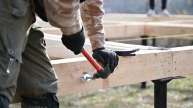 Yığınla temele ahşap çerçeve inşa eden bir işçi. Marangoz çekiçle tahta tahtaya sürgüler, çekiç kullanır. Marangozluk kavramı.