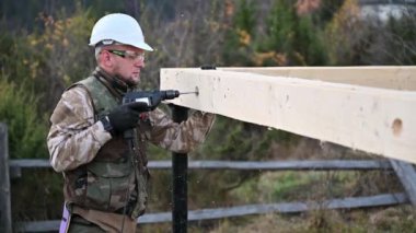 Ahşap çerçeve inşa eden adam. Gelecekteki kulübelerin ahşap çerçevesinde elektrikli matkapla delik açan işçiler. Marangozluk kavramı.