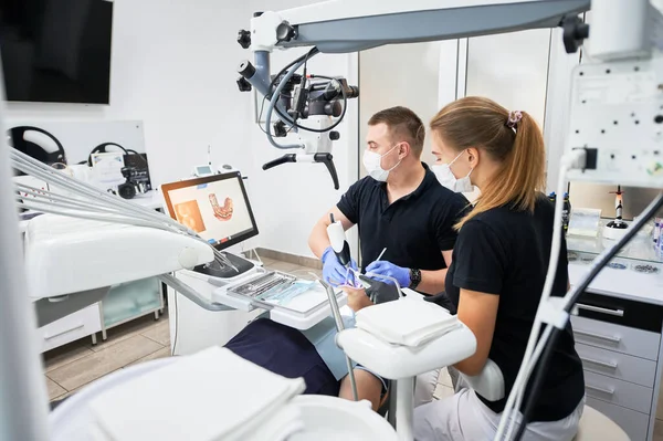 Dentist scanning patients teeth with modern machine for intraoral scanning. Digital print of patients teeth is on big screen. Modern high precision technologies. Concept of modern dentistry