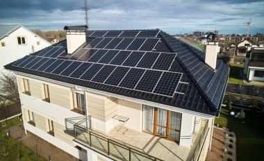 Autonomous home residence with solar panel system for generating electricity through photovoltaic effect. New two-storey house with solar modules on roof. Ecological renewable energy sources concept.