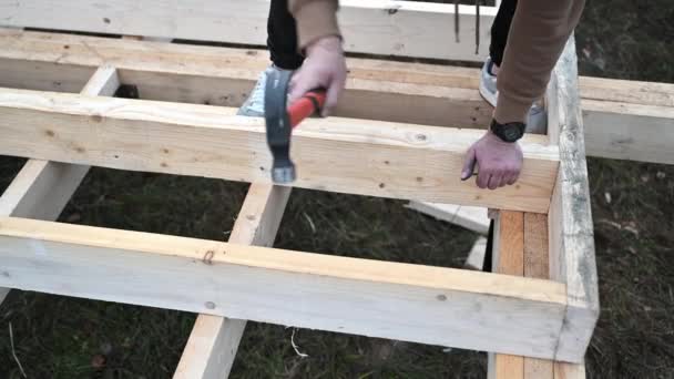 工人在桩基础上建造木制框架房屋 木匠用铁锤把钉子锤入木制桁架 木匠概念 — 图库视频影像