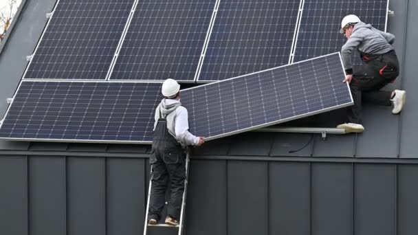 屋根の上に太陽電池モジュールステーションを構築する技術者 太陽電池パネルシステムを屋外に設置ヘルメットの男性電気技師 再生可能エネルギーの概念 — ストック動画