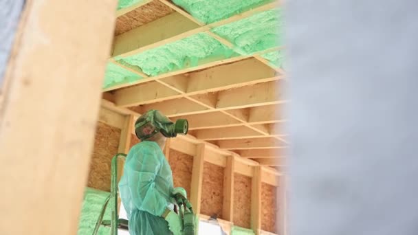 Male Builder Insulating Wooden Frame House Man Worker Spraying Polyurethane — стоковое видео