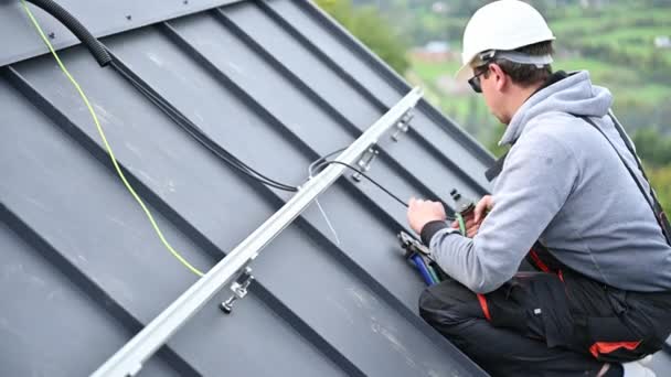 屋根の上に太陽光発電モジュールをマウントするための準備人の労働者 太陽電池パネルシステムを屋外に設置ヘルメットの電気技師 再生可能エネルギーの概念 — ストック動画