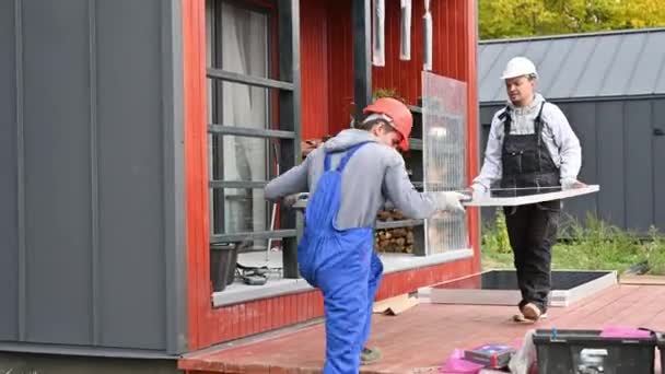 建造太阳能电池板系统的技术人员 戴钢盔的男工在室外携带光电太阳能组件 替代能源和可再生能源的概念 — 图库视频影像