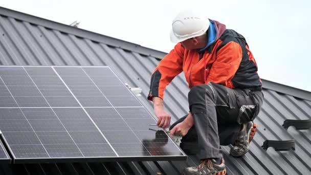 家の屋根の上に太陽光発電パネルをマウントする人技術者 六角キーの助けを借りて太陽電池モジュールシステムをインストールヘルメットのエンジニア 代替的再生可能エネルギーの概念 — ストック動画