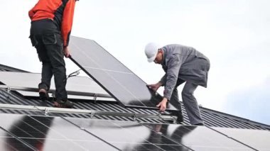 Teknisyenler evin çatısına fotovoltaik güneş modülü istasyonu inşa ediyorlar. Miğferli elektrikçiler güneş paneli sistemi kuruyor. Alternatif ve yenilenebilir enerji kavramı.