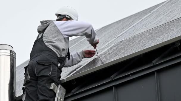 人工技术人员在房顶上安装光电太阳能电池板 头盔工程师安装太阳能模块系统 在雨中使用六角键 可再生能源的替代概念 — 图库视频影像