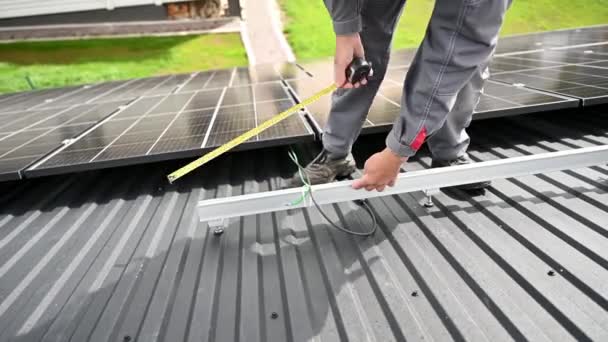 为精准计算而对合格技术人员进行测量的近景 在屋顶上调整光伏太阳能电池板 利用测量带进行太阳能电池头盔计算的工程师 — 图库视频影像