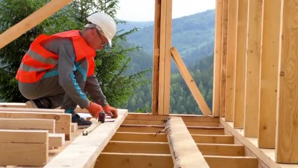 木匠在建造木制框架房屋的过程中 男人穿着工作服和头盔 用测量带测量距离 环境友好型建筑概念 — 图库视频影像