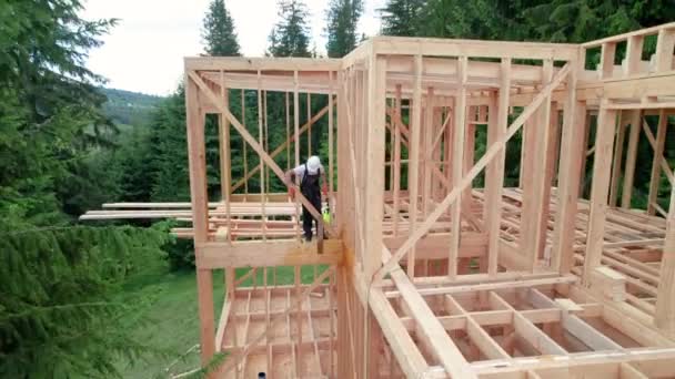 在森林附近建造木制框架房屋的工人 男人处理森林 应用阻燃剂使用喷雾器 同时穿着防护服 现代生态友好型建筑的概念 — 图库视频影像