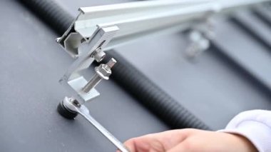 Yetkin mühendisin evin tepesindeki güneş panellerini ayarlamak için çatıdaki metal rayları emniyete almasına yakından bakın. PV sisteminin profesyonel kurulumu.