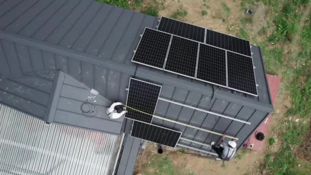 技术人员用胶带测量光伏太阳能电池板 男工在房顶安装太阳能组件发电前进行测量的空中照片 — 图库视频影像