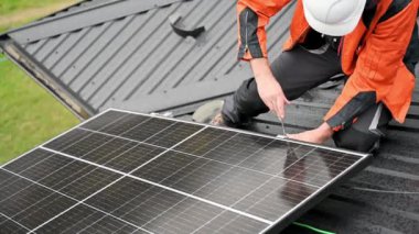 Evin çatısına fotovoltaik güneş panelleri monte eden teknisyen. Büyülü anahtarın yardımıyla güneş modülü sistemi kuran mühendisi kapatın. Alternatif, yenilenebilir enerji kavramı.